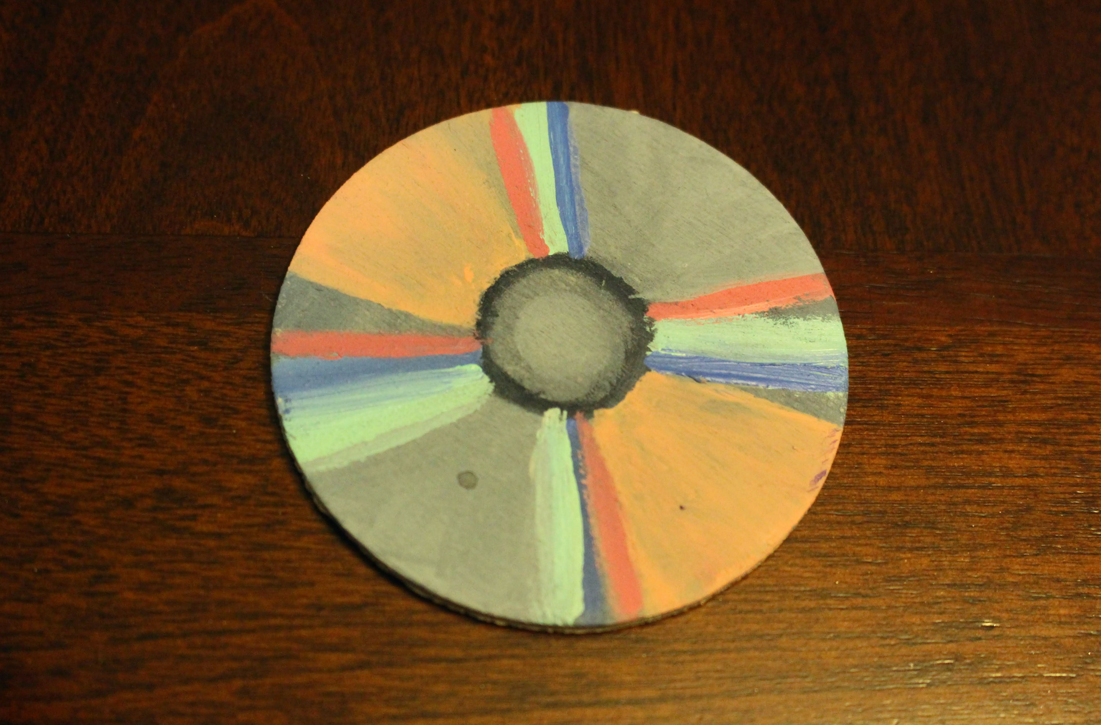 This is a painting of a CD. This was created from using acrylic on wood. This is a part of four other pieces in the kit which represent five types of devices that we used to consume hip-hop throughout the times. The CD in particular I associated with the 1990s.